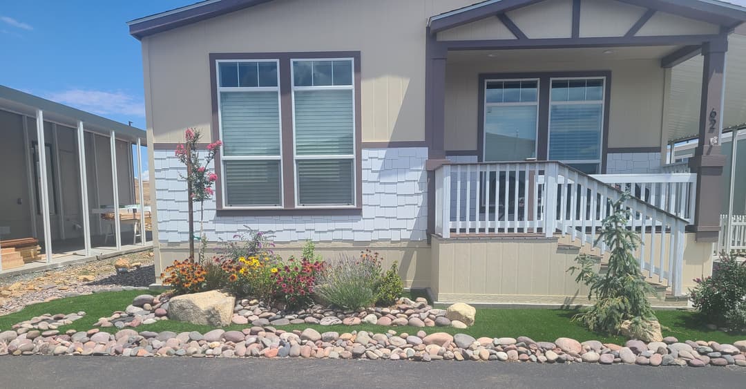 Single-story home with landscaped garden, stone borders, and colorful flowers.